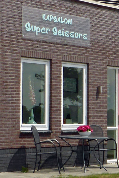 De gevel van kapsalon Super Scissors met het groene naambord